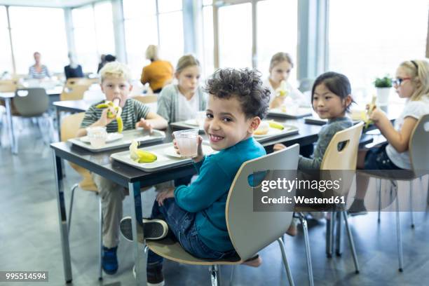 pupils having lunch in school canteen - schulessen stock-fotos und bilder
