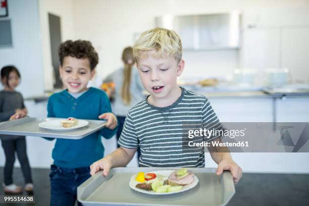 pupils carrying trays in school canteen - school dinner stock pictures, royalty-free photos & images