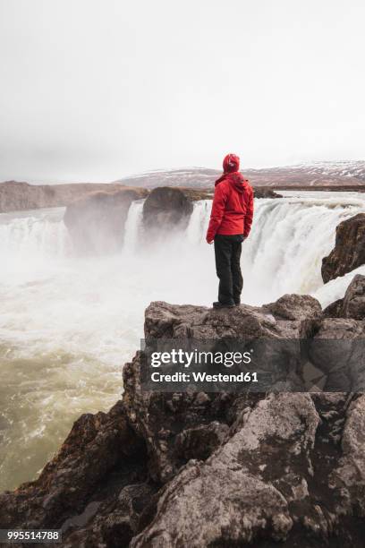iceland, man standing at godafoss waterfall - northeast iceland stockfoto's en -beelden
