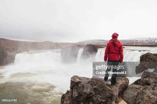 iceland, man standing at godafoss waterfall - northeast iceland stockfoto's en -beelden