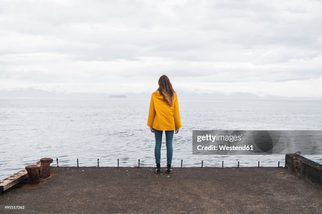 Iceland, woman standing at the sea