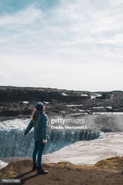 iceland, woman standing at dettifoss waterfall - dettifoss waterfall foto e immagini stock