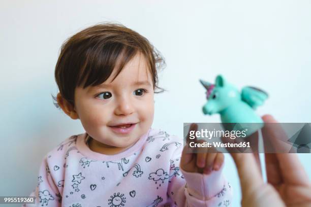 portrait of smiling baby girl looking at unicorn figure - baby pointing stockfoto's en -beelden
