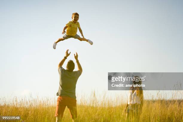 summer sunshine family pleasure little boy in the air - throwing stock pictures, royalty-free photos & images