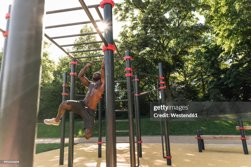 Muscular young man exercising on parcours bars