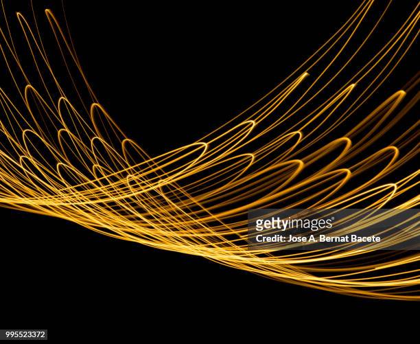 close-up abstract pattern of intertwined colorful light beams of colors yellow and gol colored on a  black background. - gol stock-fotos und bilder