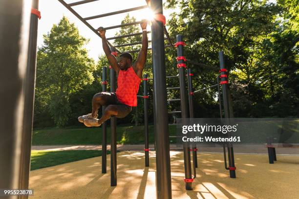 muscular young man exercising on parcours bars - horizontal bar stock pictures, royalty-free photos & images