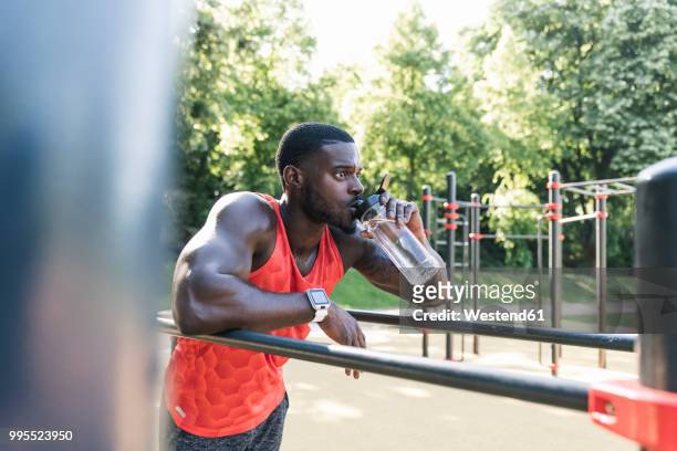 young athlete training on parallel bars, outdoors, drinking water - parallel bars gymnastics equipment stock-fotos und bilder