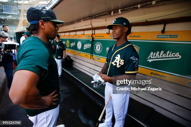 Khris Davis of the Oakland Athletics talks with first round draft pick Kyler Murray in the dugout after Murray signed his contract at the Oakland...