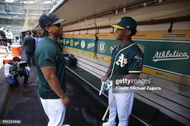 Khris Davis of the Oakland Athletics talks with first round draft pick Kyler Murray in the dugout after Murray signed his contract at the Oakland...