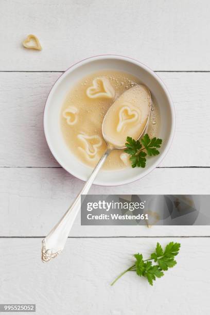 silver spoon in bowl of chicken soup with heart-shaped noodles and parsley - slätpersilja bildbanksfoton och bilder