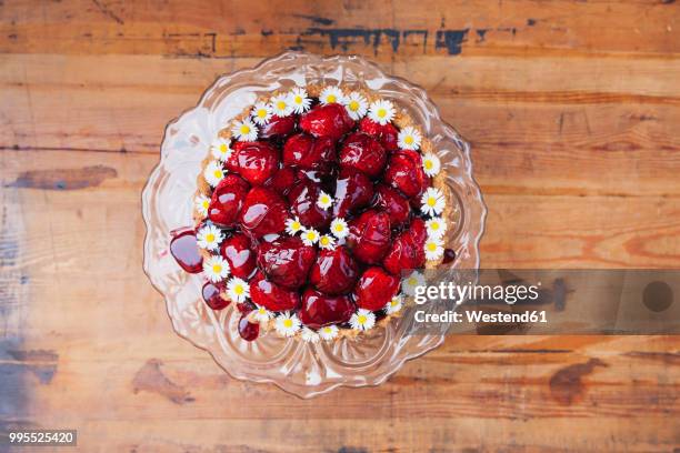 homemade strawberry cake with red grape juice glaze and daisy flower decoration on glass cake stand - cake stand stockfoto's en -beelden