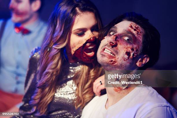 creepy woman trying to bite her boyfriend at halloween party - zombies stock-fotos und bilder