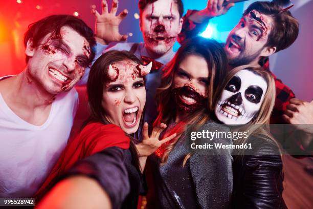 friends in creepy costumes having fun at halloween party - máscara disfarce imagens e fotografias de stock