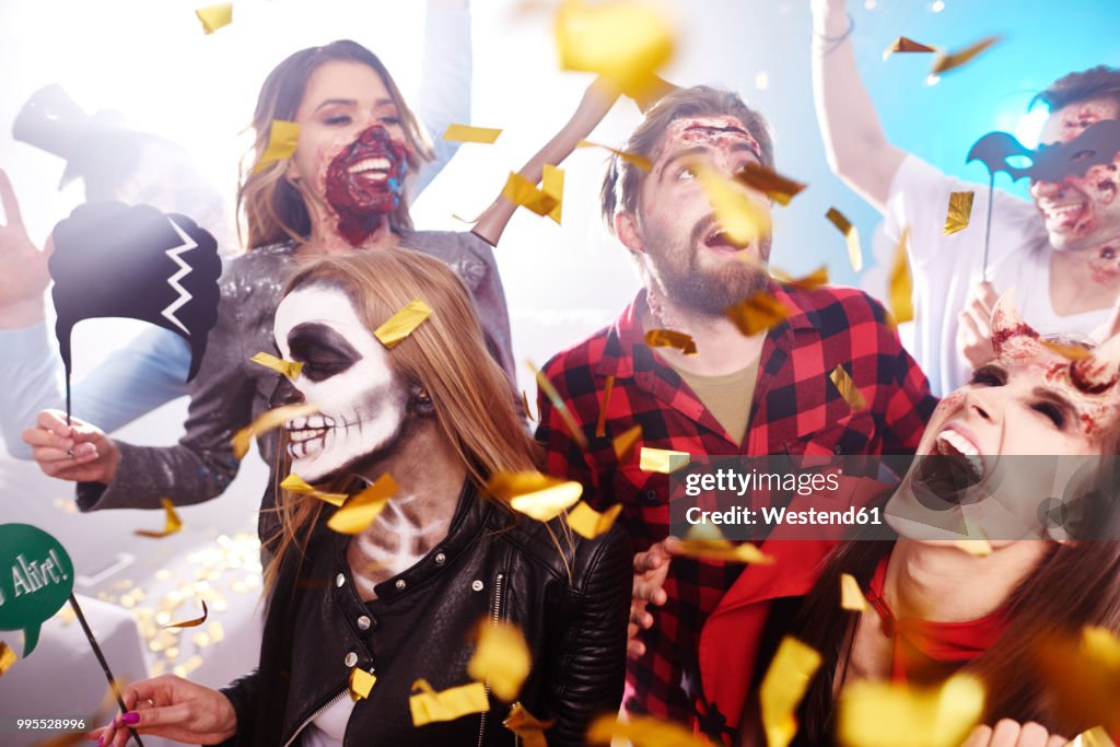 Friends in creepy costumes having fun at Halloween party