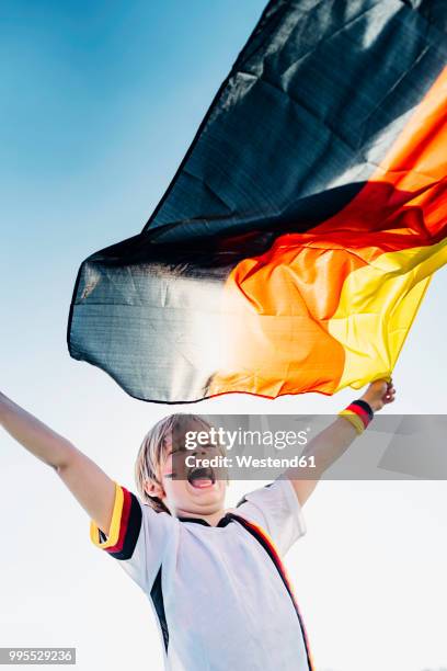 boy, enthusiastic for soccer world championship, waving german flag - germany football stock-fotos und bilder