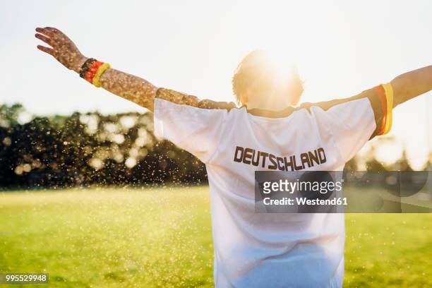 cheering boy wearing football shirt with germany written on back - trikot stock-fotos und bilder