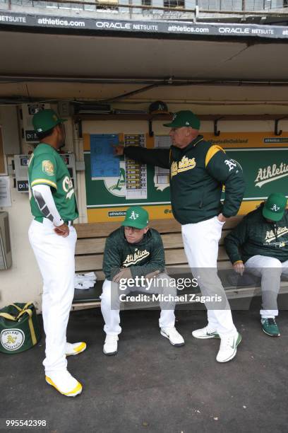 Marcus Semien, Hitting Coach Darren Bush and Third Base Coach Matt Williams of the Oakland Athletics talk in the dugout prior to the game against the...