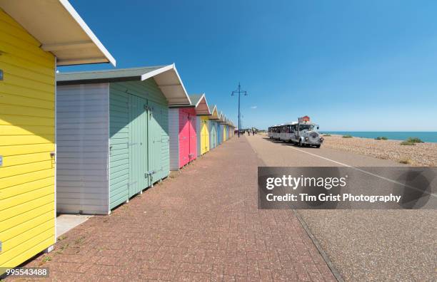 a tourist ride and beach huts on the seafront at eastbourne, east sussex - east beach stock pictures, royalty-free photos & images