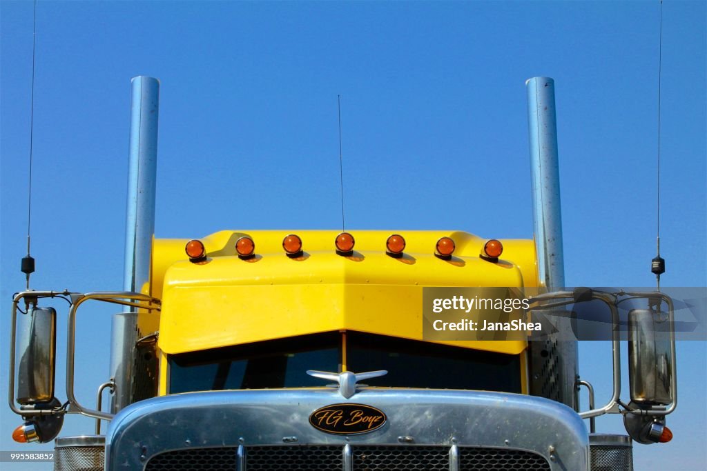 Yellow semi-truck against blue sky