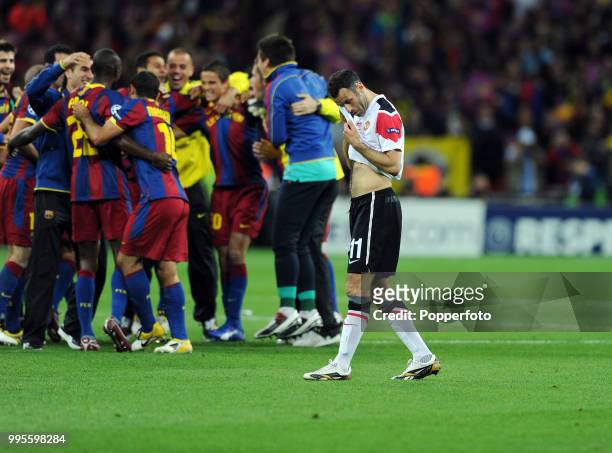 Dejected Ryan Giggs of Manchester United and the celebratory FC Barcelona team following the UEFA Champions League final between FC Barcelona and...