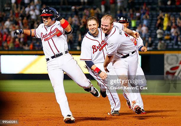 Martin Prado of the Atlanta Braves runs away from Brian McCann and Eric Hinske after hitting a two-run single in the bottom of the ninth inning to...