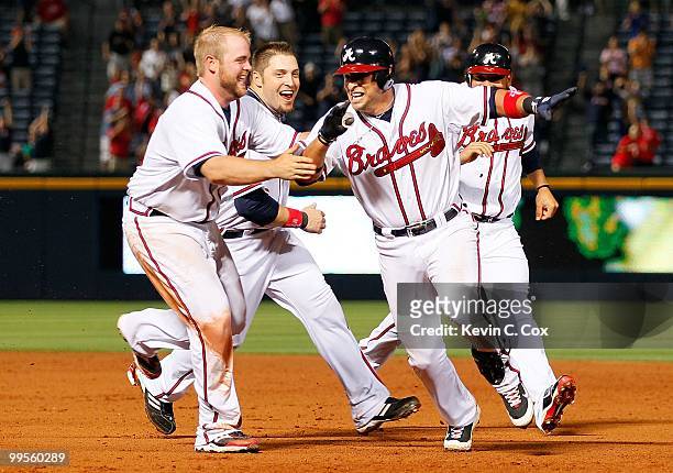 Martin Prado of the Atlanta Braves runs away from Brian McCann and Eric Hinske after hitting a two-run single in the bottom of the ninth inning to...