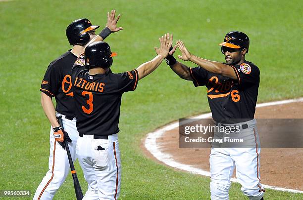 Corey Patterson of the Baltimore Orioles celebrates with Luke Scott and Cesar Izturis after scoring in the sixth inning against the Cleveland Indians...