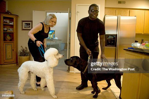 Michele Weil keeps her poodle "Max Fax" at bay as Mario Bonds arrives with his dog "Sidney" at her home in Rockville, Maryland, on Friday, May 14,...