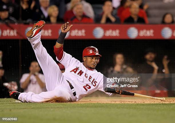 Erick Aybar of the Los Angeles Angels of Anaheim slides safely across home plate while grabbing a bat and scores on a base hit by Kendry Morales in...