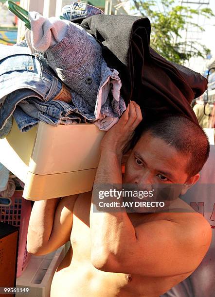 Man carries items salvaged from his home that was burned in a fire in a slum area in Muntinlupa city suburban Manila on May 15, 2010. The huge fire...