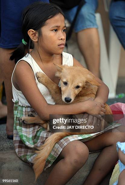 Young girl holds her pet dog after a fire raged through a slum area in Muntinlupa city suburban Manila on May 15, 2010. The huge fire that engulfed a...