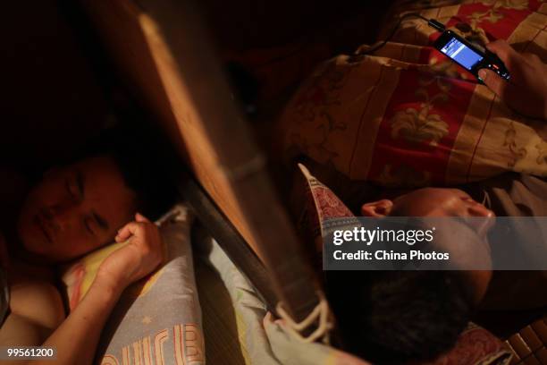 Migrant workers 31-year-old Jiang Zhaoqi sleeps as 26-year-old Gong Bingan chats with Tencent QQ, a popular instant messaging computer program...