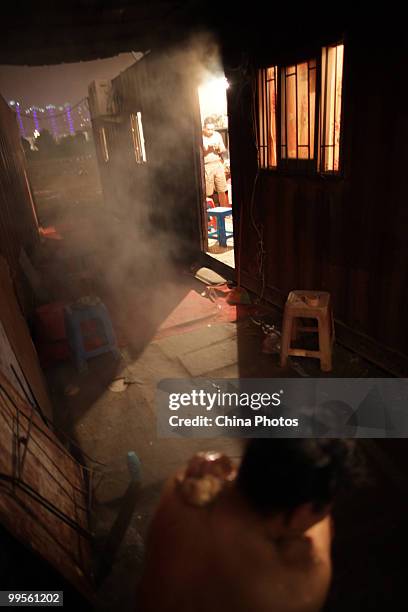 Migrant worker 44-year-old Dou Tingfu, who lives in a shipping container house at the south bank of the Minjiang River, baths after 16 hours work on...