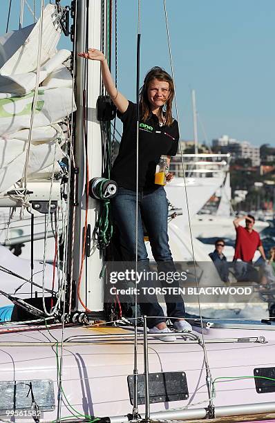 Australian round-the-world sailor, Jessica Watson, waves to a flotilla of well-wishers as her yacht 'Ella's Pink Lady' crosses the official finish...