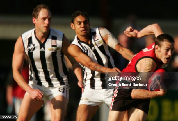 Josh Fraser and Brad Dick of Collingwood tackle Warwick Miller of Frankston during the round six VFL match between Collingwood and Frankston at...