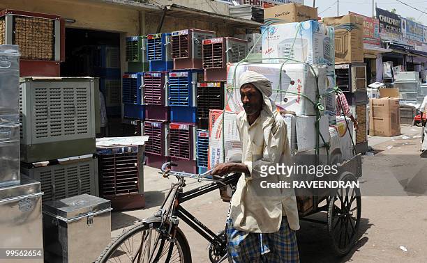 An Indian worker transports newly-purchased air coolers on his bicycle cart, to be delivered to customers, at a market in New Delhi on May 15 as...