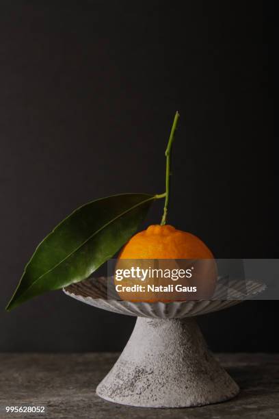 mandarin on a gray vintage bowl on a gray stone background - tangerine 2015 film stock-fotos und bilder