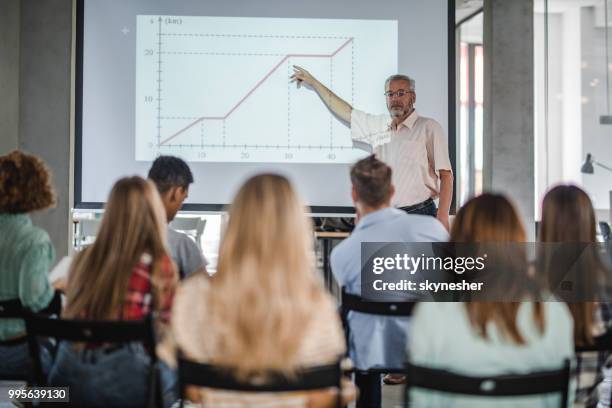 professore maturo che dà una presentazione a un ampio gruppo di studenti. - conference large screen foto e immagini stock