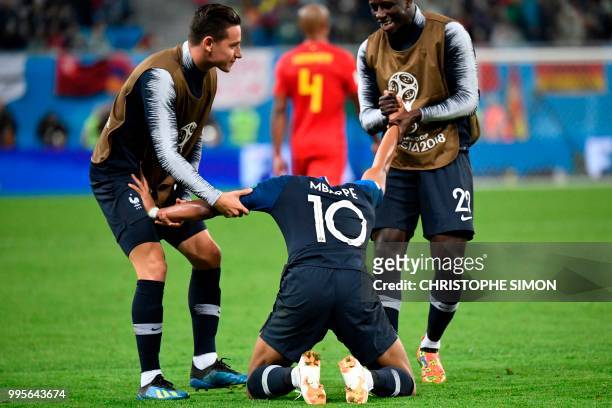 France's forward Florian Thauvin and France's defender Benjamin Mendy pull France's forward Kylian Mbappe's arms as they celebrate at the end of the...