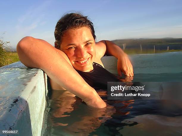 young woman in hot spa enjoying the midnight sun - northeast iceland stockfoto's en -beelden