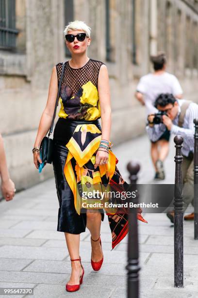 Elisa Nalin wears a black mesh top, a black satin skirt, a yellow and red piece of dress, red shoes , outside Givenchy, during Paris Fashion Week...