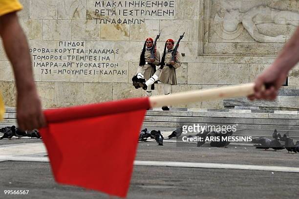 Greek presidential guards perform on the tomb of the unknown soldier as communist demonstrators of the KKE march outside the parliament on May 15,...