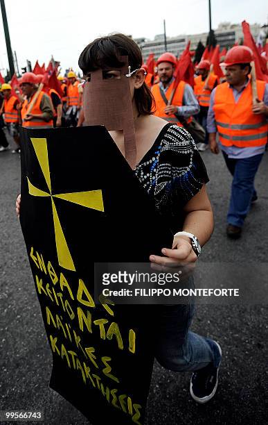 Communist demonstrato of the KKE holds a banner shaped like a coffin reading " here we have buried all our social conquests" as she marches through...