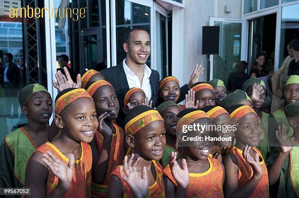 In this handout image provided by Amber Lounge, Lewis Hamilton poses with the African Childrens choir at the Amber Lounge party held at Meridien...