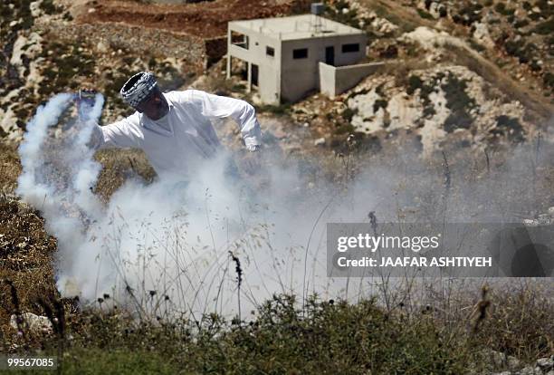 Palestinian protester throws back a tear gas canister fired by Israeli soldiers during a demonstration against the expansion of Jewish settlements in...