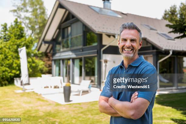 portrait of happy mature man in garden of his home - mann vor haus stock-fotos und bilder