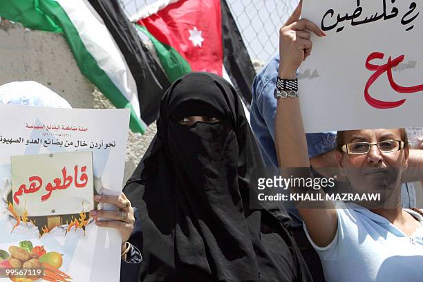 Conservative Muslim woman stands next to a placard with the slogan "boycott them" during a demonstration in the Jordanian capital Amman on May 15,...