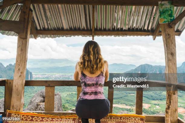 laos, vang vieng, young woman in a hut overlooking landscape of rice fields - westend61 stockfoto's en -beelden