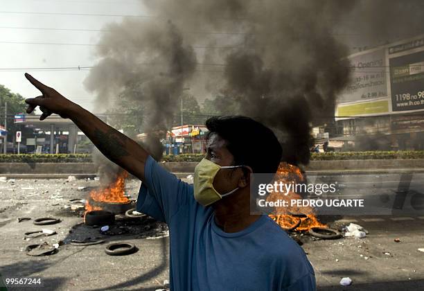 Demonstrator points towards Thai soldiers during clashes in Bangkok on May 15, 2010. Six people were killed and 31 injured in fresh violence as...